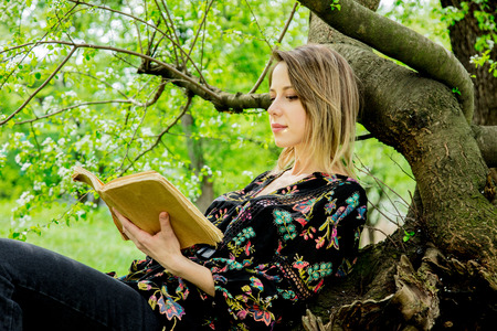 Young caucasian woman with book in springtime park.