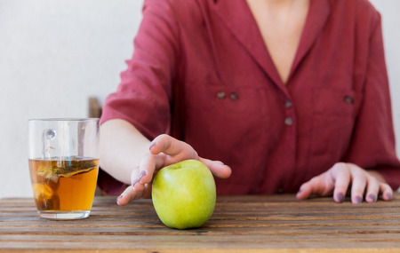 Beautiful woman with tea cup and apple at home in a morning. Breakfast timeの写真素材