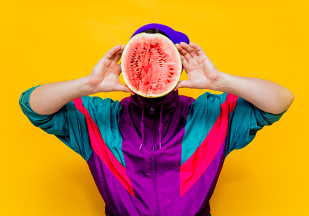 Young man in 90s clothes with watermelon on yellow background.の写真素材