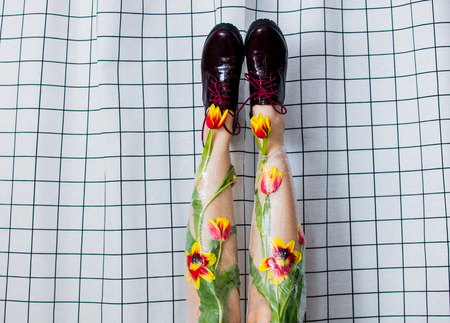 woman holds her legs up wrapped with cellophane and tulips flowers.の写真素材