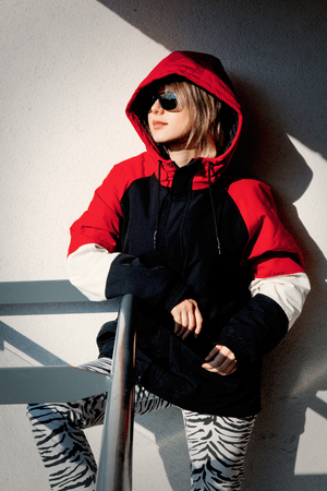 Style girl in jacket with hood stay on balcony with shadows.の写真素材