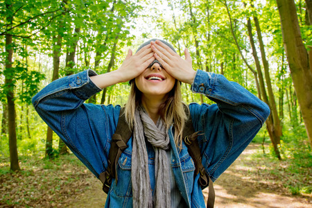 Young woman with backpack hide face with a scarf in a mixed forest Beskidy in Poland in spring time.の写真素材