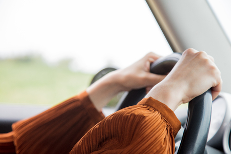 Female holding hands on a steering wheel in a car. Closeup viewの写真素材