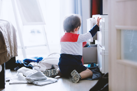 Child makes a mess in the closet at homeの写真素材