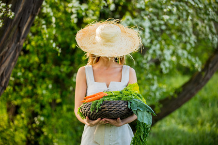 Young woman with vegetable basket at spring time outdoorの写真素材