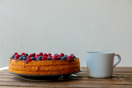 Chocolate covered blueberry and raspberry tart with coffee cupの写真素材