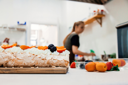 Confectioners make meringue cake with cream on tableの写真素材