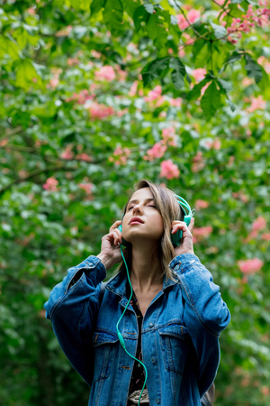 Woman with a headphones at blossom trees on background in springtimeの写真素材