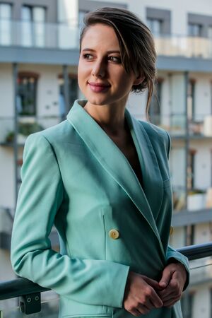 Beautiful woman in blue jacket at balcony of apartmentsの写真素材