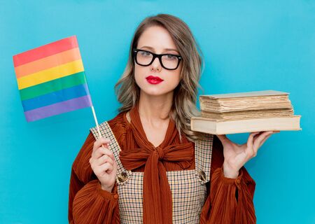 Young woman with books and LGBT flag on blue bckgroundの写真素材