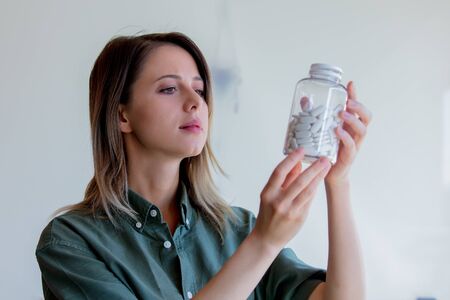 Woman holding a transparent jar with white pillsの写真素材