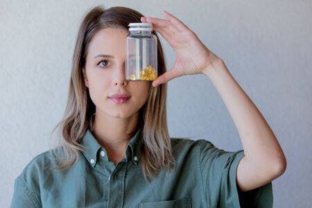 Woman keeps transparent jar with pills at eye level. Side viewの写真素材