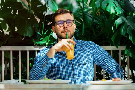 young handsome man drinking juice in a cafe