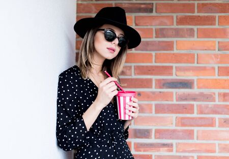 Young woman in hat and sunglasses with a drinkの写真素材