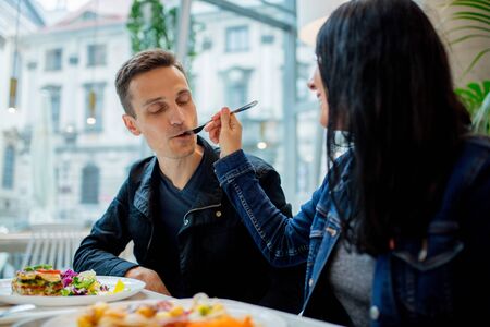 Young man eating salad from a fork in a cafeの写真素材