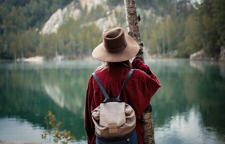 woman in hat and red shirt near lake in a mountains.の写真素材
