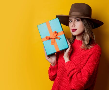 Young surprised woman in red sweater with gift boxの写真素材