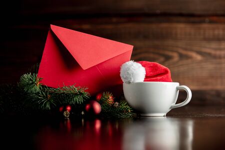 Santa Claus hat and cup with envelope on wooden table and backgroundの写真素材