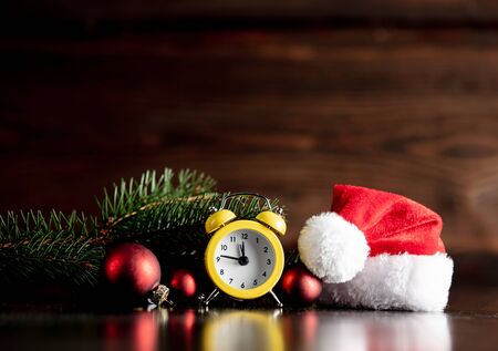 Santa Claus hat and alarm clock on wooden table and backgroundの写真素材