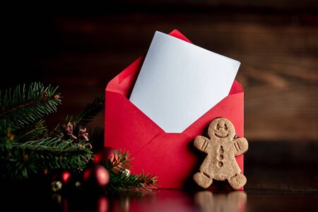 Gingerbread man and Christmas tree with red envelope on wooden tableの写真素材