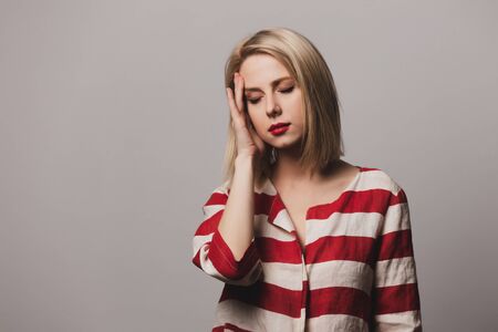 beautiful blonde woman in striped jacket hold headの写真素材