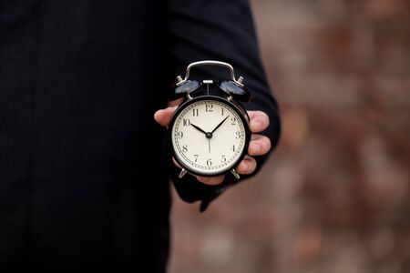 Man holding an alarm clock at outdoor.の写真素材