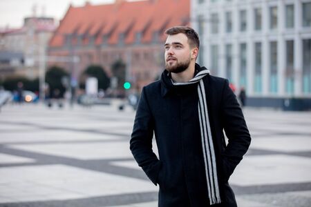 Handsome man in scarf and coat on city streetの写真素材