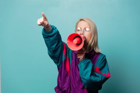 Style blonde woman in glasses with loudspeaker on blue background
