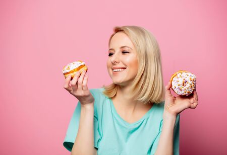 Beautiful blonde woman with donut on pink backgroundの写真素材