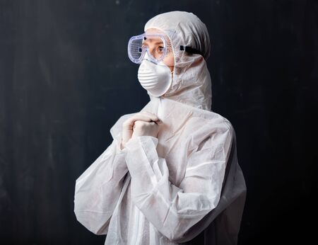 medic woman wearing protective clothing against the virus is pray