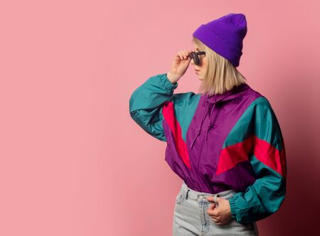 Beautiful blonde woman in sunglasses and 90s clothes on pink background