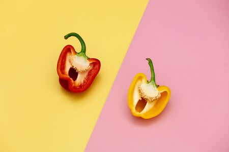 cut red and yellow peppers on pink and yellow backgroundsの写真素材