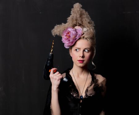 Beautiful blonde countess with a drill on dark background