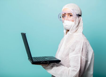 medic woman wearing protective clothing against the virus with laptop computer on a blue backgroundの写真素材
