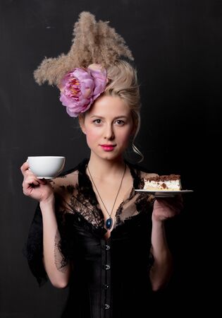 Beautiful blonde countess with cake and cup on dark background