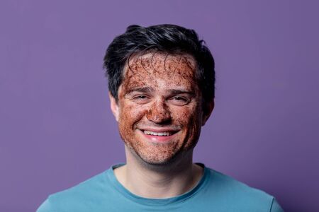 smiling guy in a face care mask on a purple background