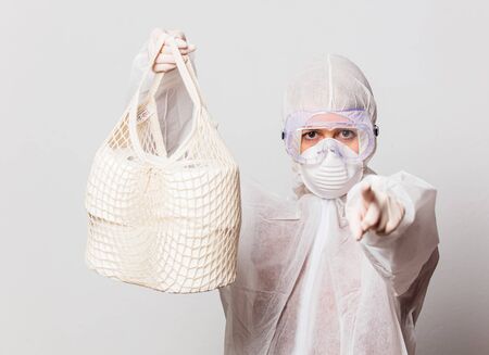 female in protection suit and glasses with mask holds toilet paper