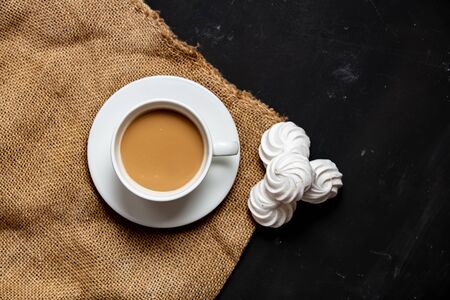 White cup of coffee and meringue on dark backgroundの写真素材