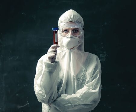Doctor in protection clothes holds COVID-19 vaccine