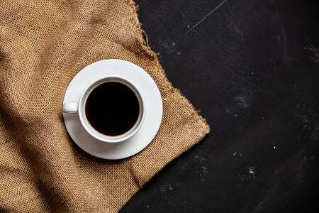 cup of black coffee and jute bag on dark backgroundの写真素材