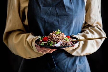 woman in an apron holds a plate of buckwheat in her handsの写真素材