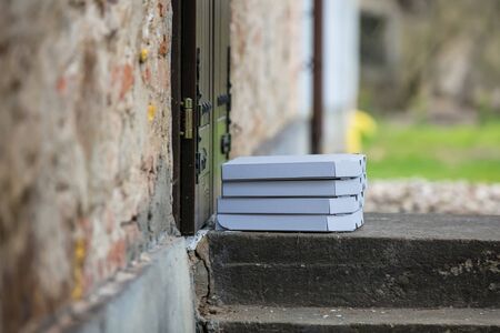 Pizza in a box left by deliveryman near a doorの写真素材