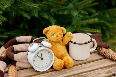 cup of coffee and teddy bear on wooden table with spruce branches on backgroundの写真素材