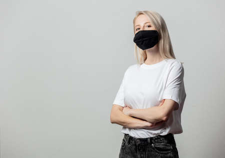Woman in white t-shirt and black face mask on white backgroundの写真素材