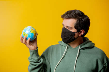 guy in facemask hold Earth globe on yellow backgroundの写真素材