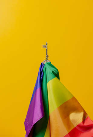golden key and LGBT flag on yellow background