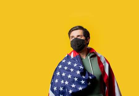 guy in facemask hold USA flag on yellow backgroundの写真素材