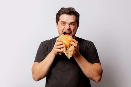 White man in black shirt with burger on white background