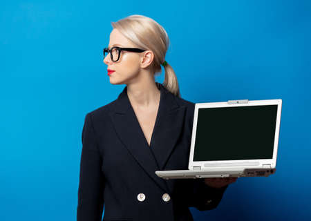 Style blonde in black jacket with notebook computer on blue background