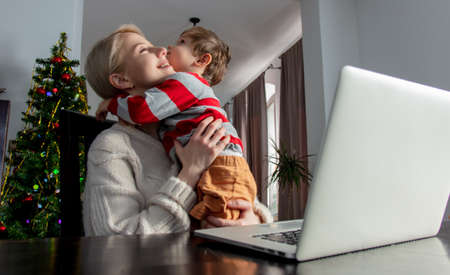businesswoman with a child is working with laptop at home office during pandemicの写真素材